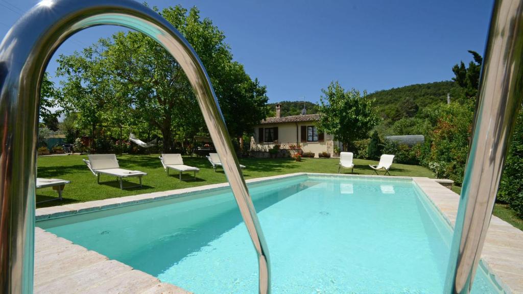 un miroir reflétant une piscine avec des chaises et une maison dans l'établissement Sferracavalli 4, Emma Villas, à Sarteano