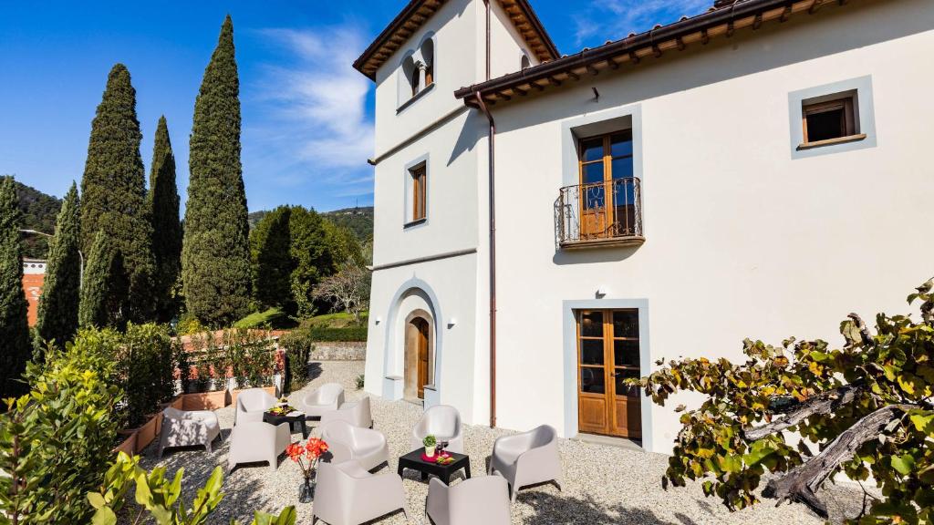une vue extérieure d'une maison blanche avec des meubles blancs et des arbres dans l'établissement TORRE ANGELINA 10&2, Emma Villas, à Montecatini Terme