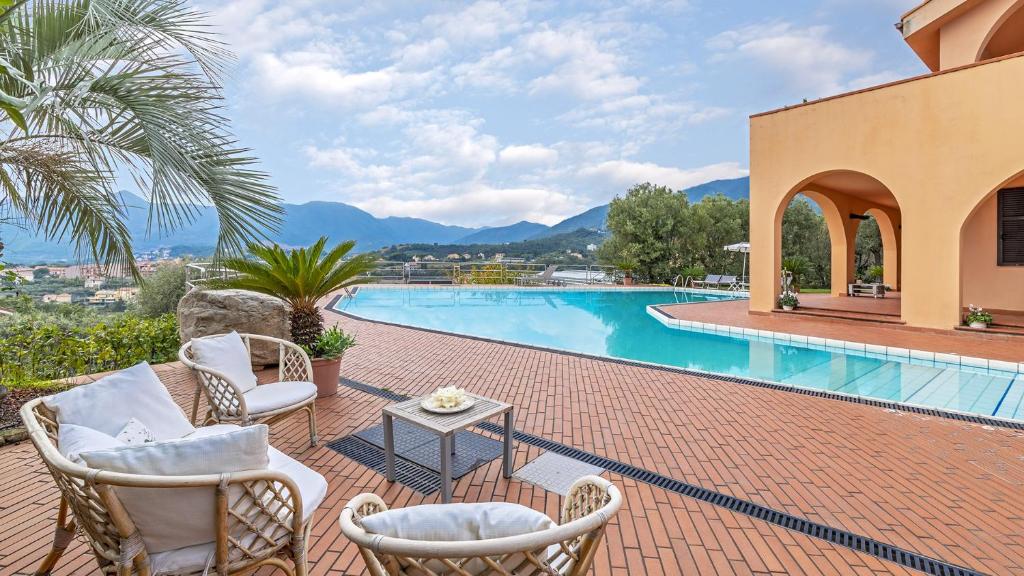 un patio avec des chaises et une table à côté d'une piscine dans l'établissement VILLA ELDA 6, Emma Villas, à Loano