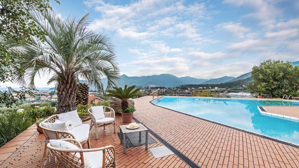 - une piscine avec des chaises, une table et un palmier dans l'établissement VILLA ELDA 6, Emma Villas, à Loano