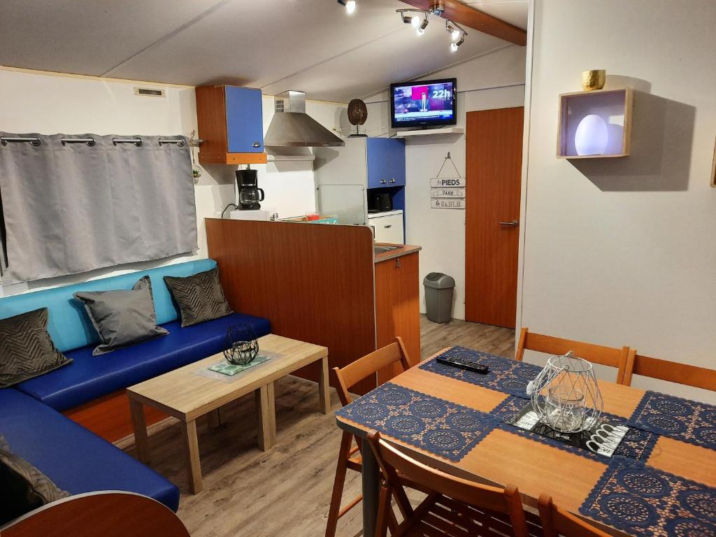 un salon avec un canapé bleu et une table dans l'établissement Location mobil home, à La Baule