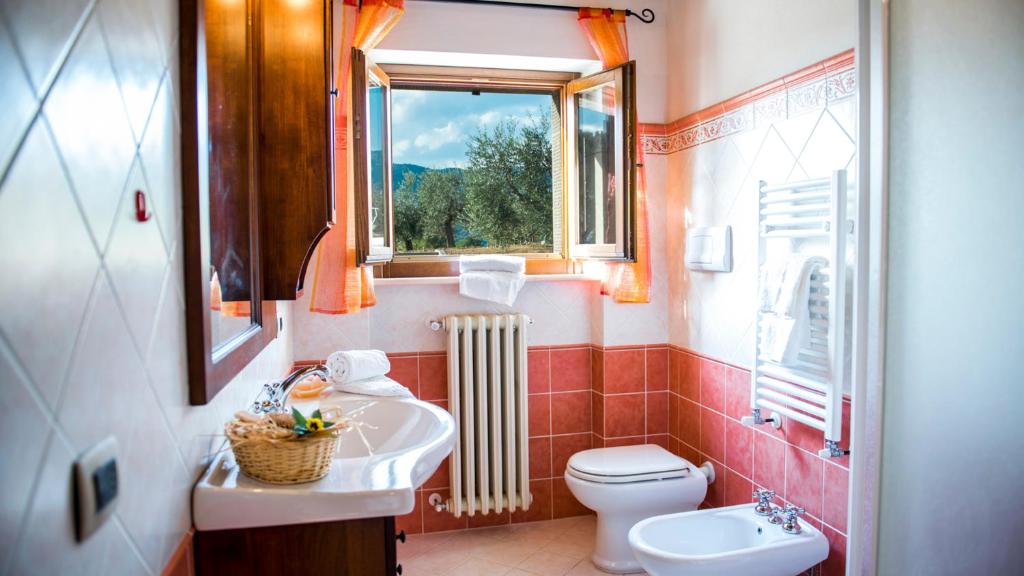 une salle de bain avec un lavabo et des toilettes et une fenêtre dans l'établissement Vinciluna 4, Emma Villas, à Cortone
