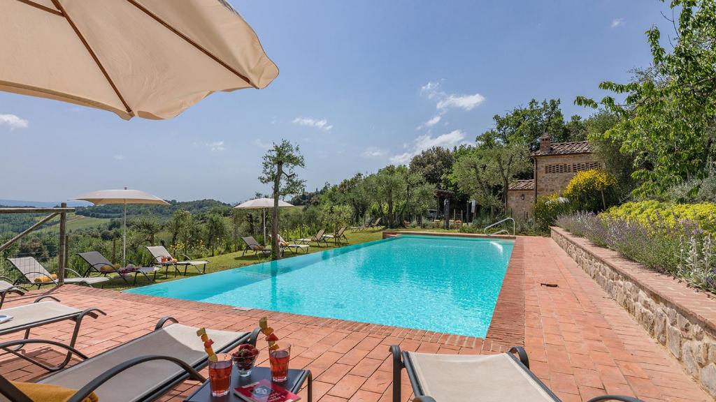 une piscine avec des chaises et un parasol dans l'établissement Villa Santa Maria 14, Emma Villas, à San Gusmè