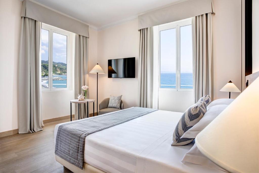 une chambre d'hôtel avec un grand lit et des fenêtres dans l'établissement Grand Hotel Arenzano, à Arenzano
