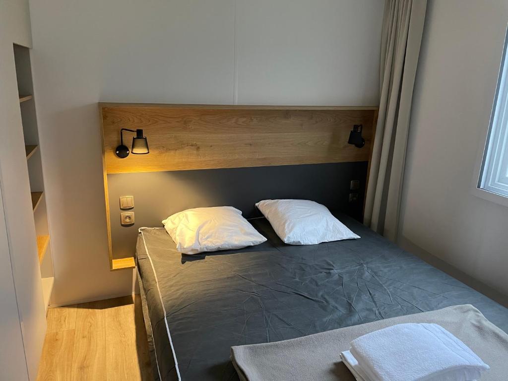 une chambre avec un lit avec deux oreillers dessus dans l'établissement Mobilhome tout confort R10 domaine de lanniron, à Quimper 10 autres photos