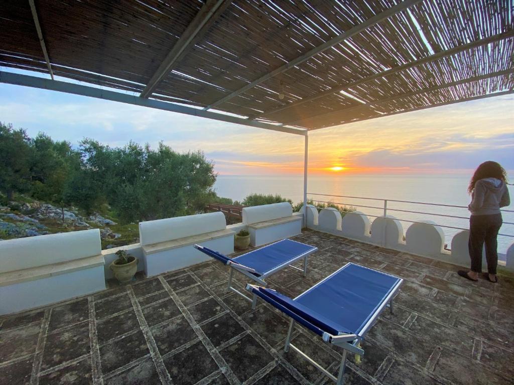 une femme debout sur un balcon avec des chaises et des tables dans l'établissement Villa Aurora, à Corsano