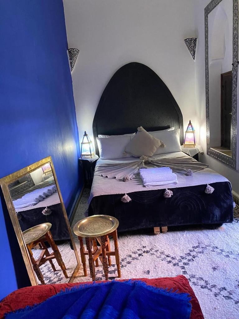 une chambre avec un lit, un miroir et une chaise dans l'établissement Riad Naya, à Marrakech