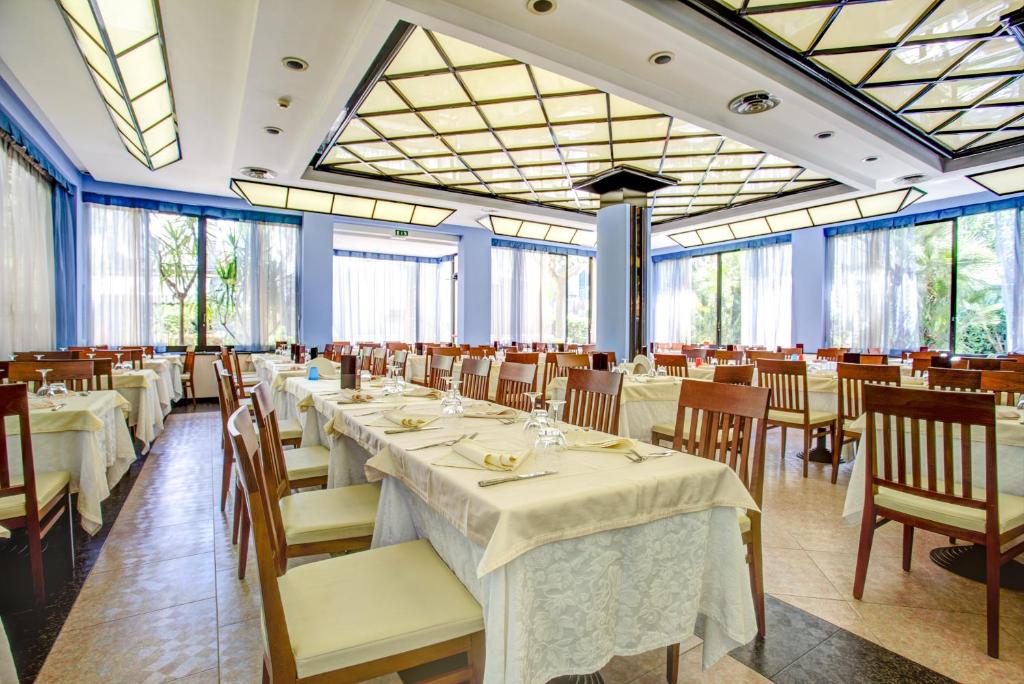 une salle à manger avec tables, chaises et fenêtres dans l'établissement Hotel Rosalba - Valentini Family Village, à Bellaria-Igea Marina