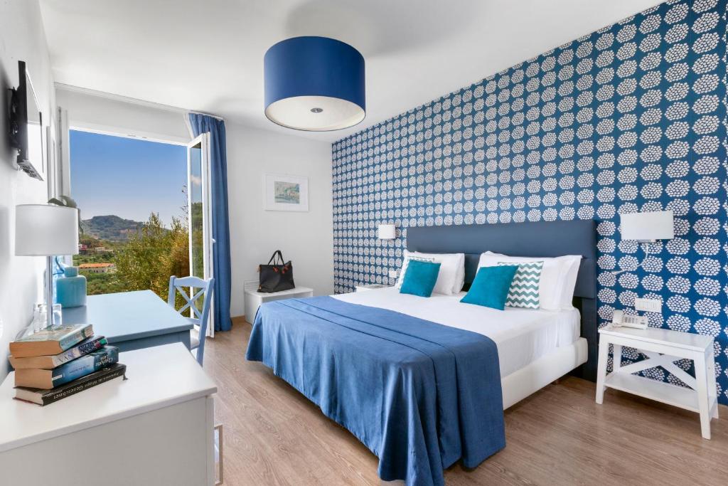 - une chambre bleue et blanche avec un lit et une fenêtre dans l'établissement Hotel Vista di Capri, à Massa Lubrense