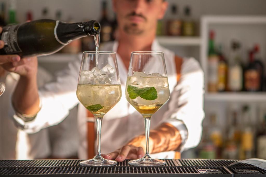 un barman verse deux verres de vin blanc dans l'établissement Hotel Vista di Capri, à Massa Lubrense