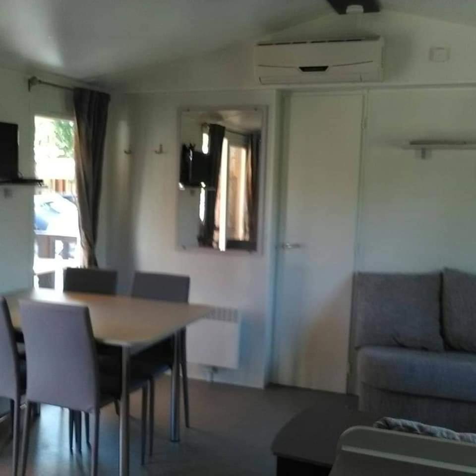 un salon avec une table, des chaises et un canapé dans l'établissement Mobil home Stéfie, à Vias