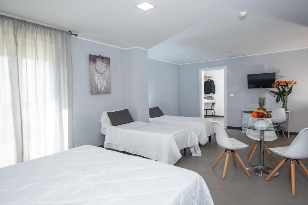 Cette chambre blanche comprend deux lits et une table. dans l'établissement Hotel Club Eloro, à Noto Marina 65 autres photos