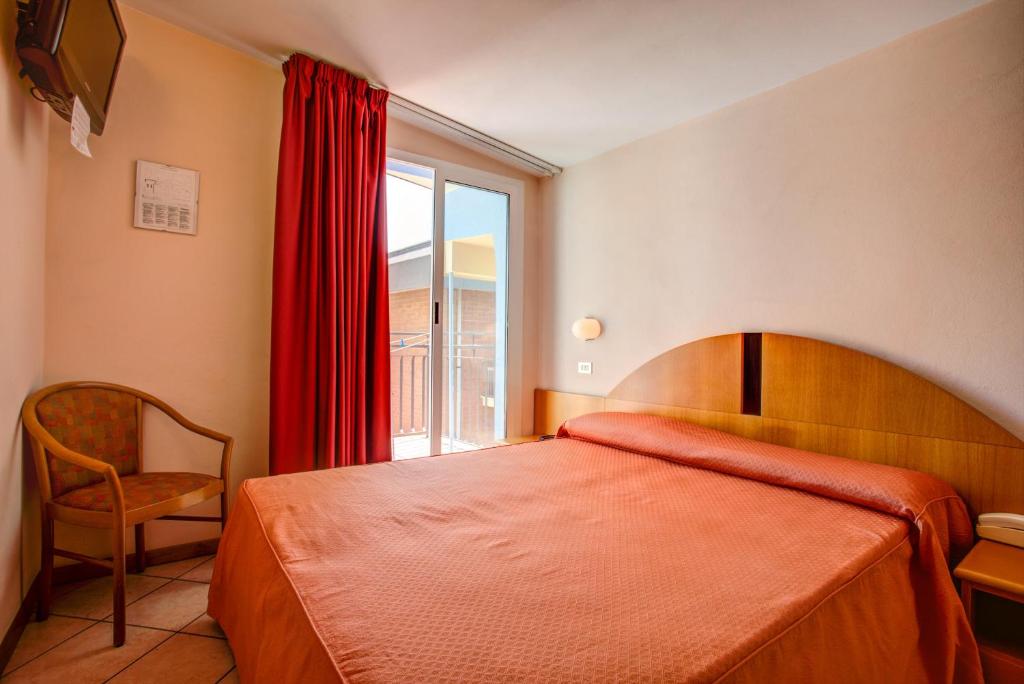 une chambre avec un lit, une chaise et une fenêtre dans l'établissement Hotel Rosalba - Valentini Family Village, à Bellaria-Igea Marina