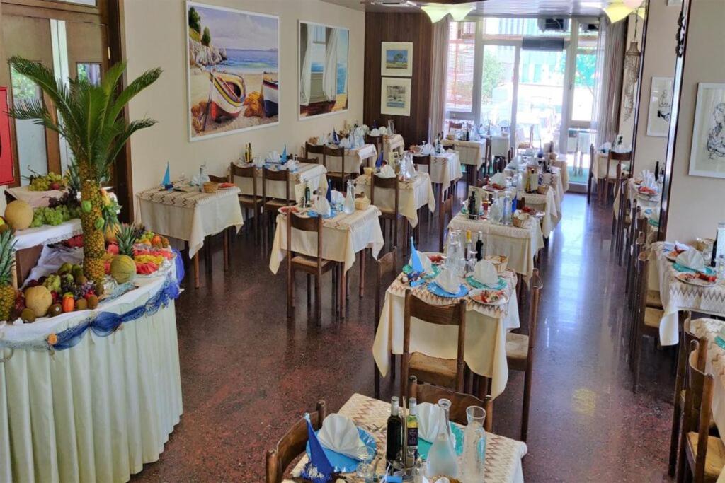 une salle à manger remplie de tables avec des nappes blanches dans l'établissement Hotel President, à San Benedetto del Tronto