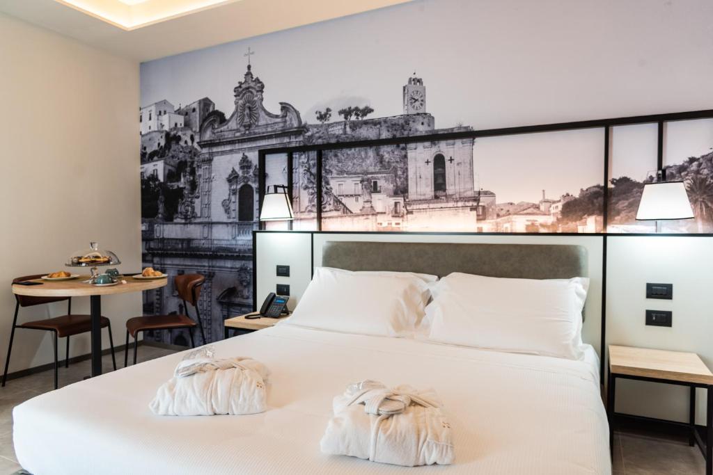 une chambre avec un grand lit blanc avec un tableau sur le mur dans l'établissement Modica Boutique Hotel, à Modica