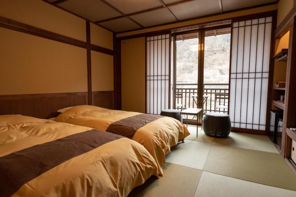 deux lits dans une chambre avec deux fenêtres dans l'établissement Shima Onsen Kashiwaya Ryokan, à Nakanojo