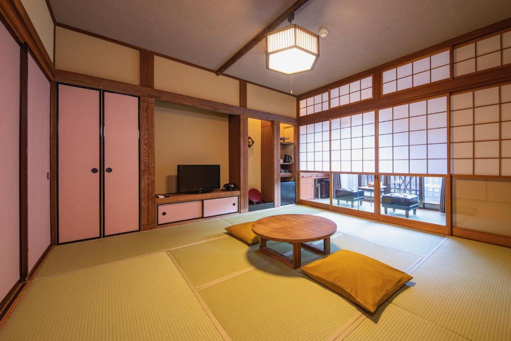 un salon avec une table et une télévision dans l'établissement Shima Onsen Kashiwaya Ryokan, à Nakanojo