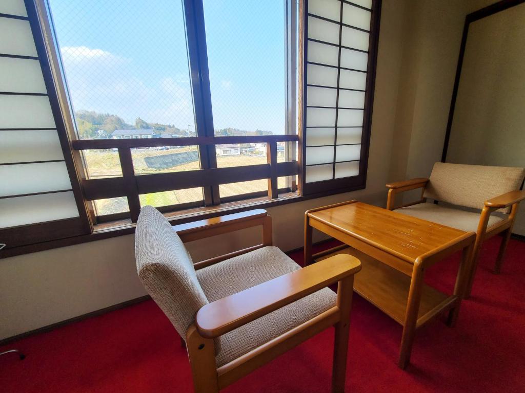 une pièce avec une table, des chaises et des fenêtres dans l'établissement Iris Yu, à Hiraizumi