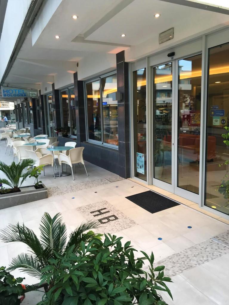 un restaurant avec des tables et des chaises dans un bâtiment dans l'établissement Hotel Bologna, à Lignano Sabbiadoro
