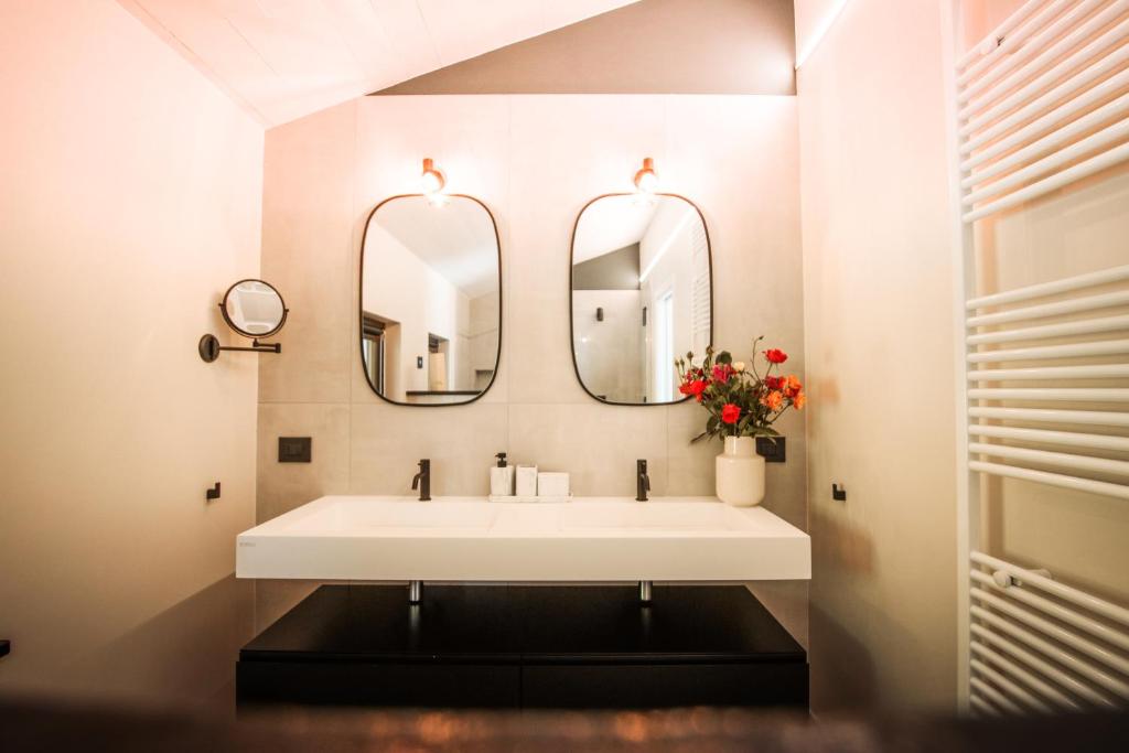 une salle de bain avec un lavabo blanc et deux miroirs dans l'établissement Villa Monforte Barolo with private pool - LANGHE GATEWAY, à Monforte dʼAlba