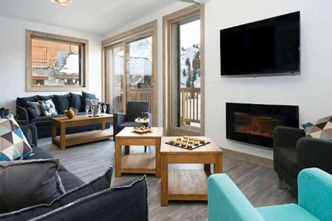 un salon avec un canapé et une cheminée dans l'établissement Résidence Carlina by Les Etincelles, à Belle Plagne