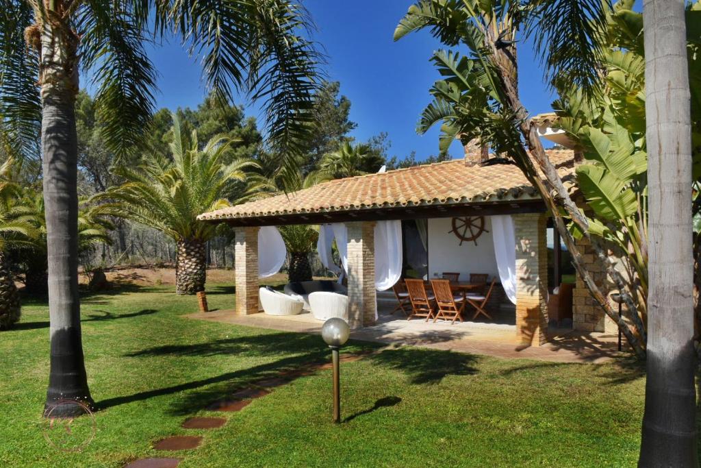 une maison avec une véranda ornée de palmiers dans l'établissement Villa Palmetto, à Forte Village
