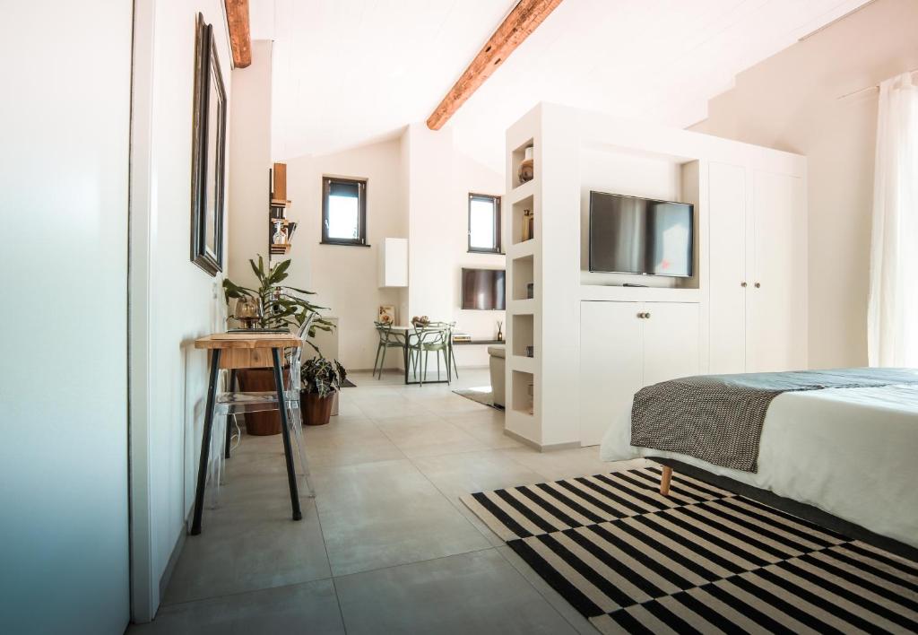 une chambre blanche avec un lit et une télévision dans l'établissement Villa Monforte Barolo with private pool - LANGHE GATEWAY, à Monforte dʼAlba 33 autres photos