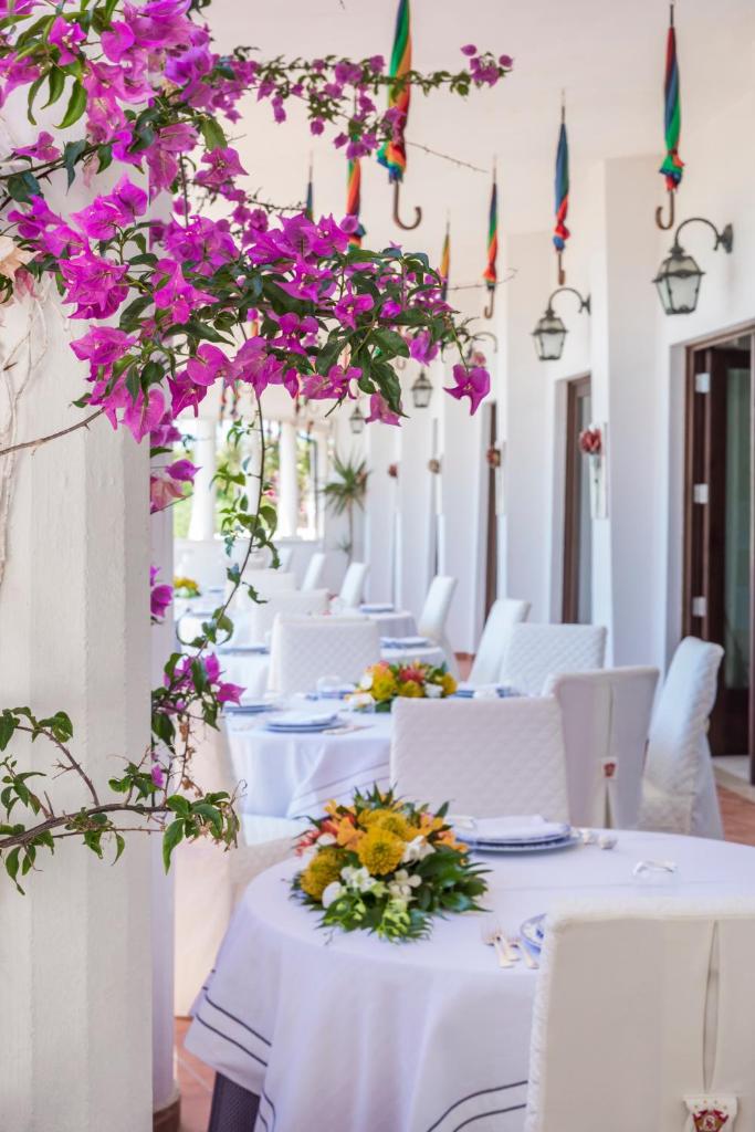 une salle à manger avec des tables blanches et des fleurs violettes dans l'établissement Hotel Lido degli Scogli, à Crotone