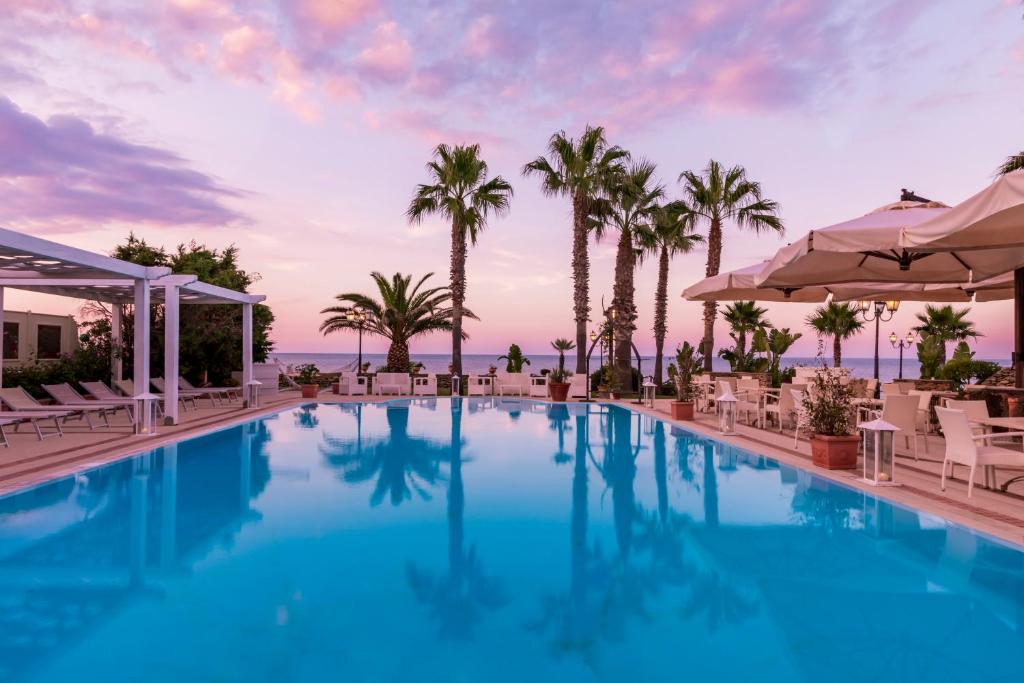 une piscine avec des chaises et des palmiers dans l'établissement Hotel Lido degli Scogli, à Crotone