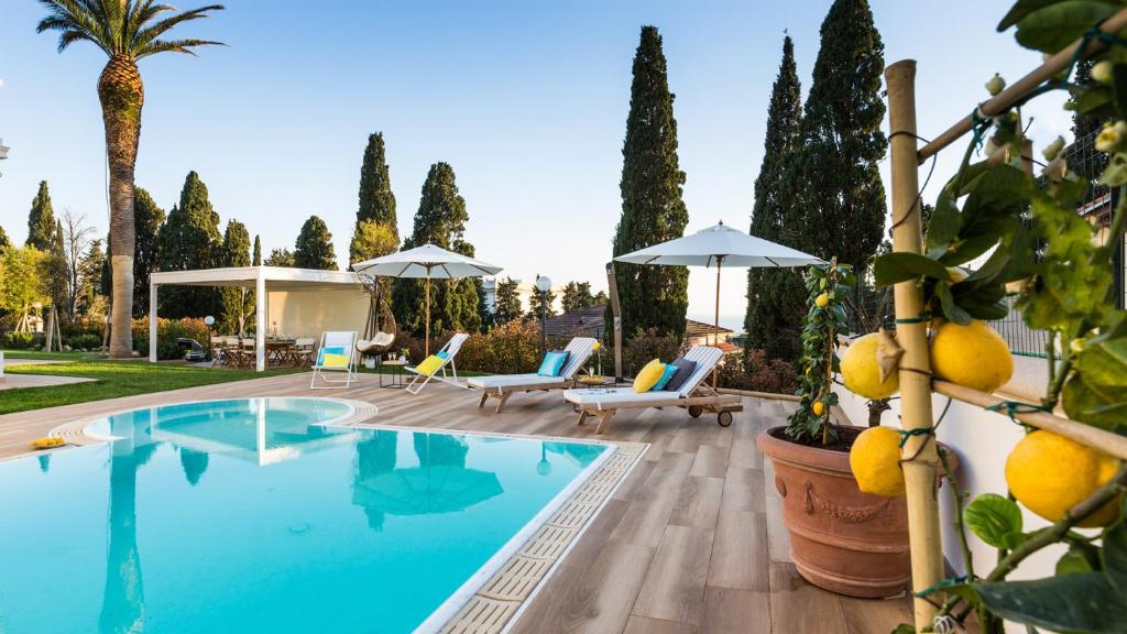 une piscine avec des chaises et des parasols dans une cour arborée dans l'établissement Villa Sole Al Molino A Vento 8, Emma Villas, à Rosignano Marittimo