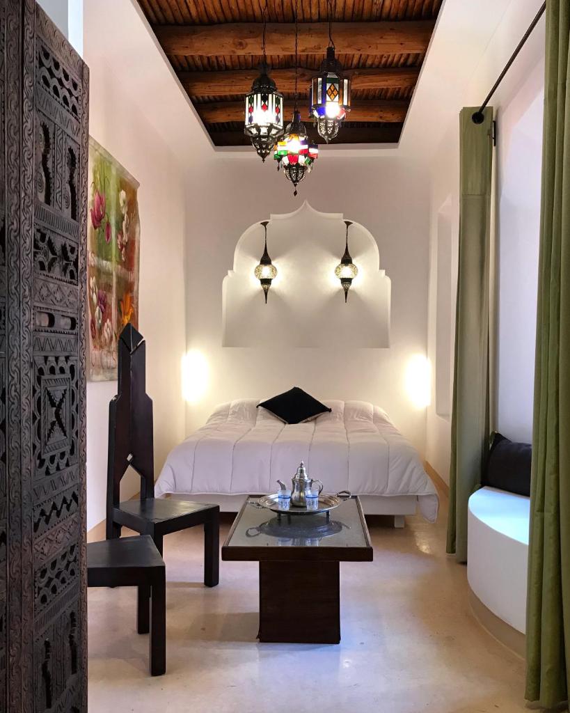 - une chambre avec un lit, une table et un lustre dans l'établissement Riad Zahir, à Marrakech