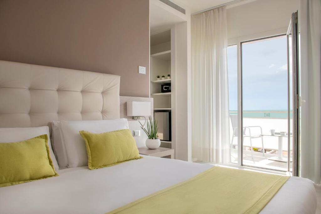 une chambre avec un grand lit blanc avec une grande fenêtre dans l'établissement Hotel Delle Rose, à Lido di Jesolo