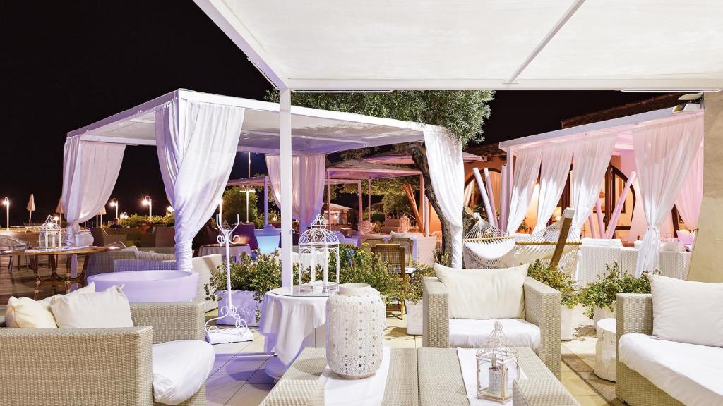 une pièce avec des chaises et des tables blanches et une tente dans l'établissement Hotel Baia Del Porto, à Budoni 74 autres photos