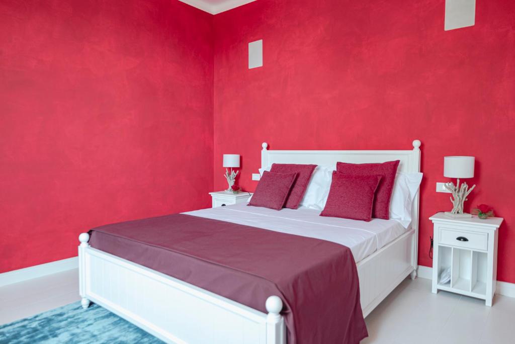 une chambre avec des murs rouges et un lit blanc avec des oreillers rouges dans l'établissement Cà del Mago Pool garden & spa, only adults, à Lerici
