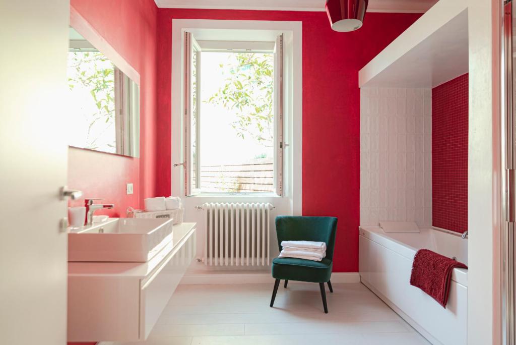 La salle de bains est pourvue de murs rouges et d'une chaise verte. dans l'établissement Cà del Mago Pool garden & spa, only adults, à Lerici
