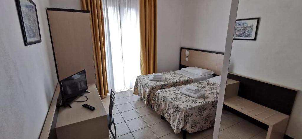 une petite chambre avec deux lits et une télévision dans l'établissement Hotel Rondine, à Marinella di Sarzana