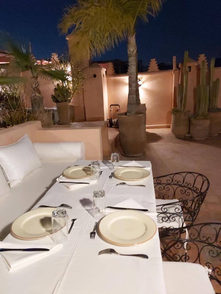 - une table avec des plaques blanches et de l'argenterie sur une terrasse dans l'établissement Riad Les Nuits de Marrakech, à Marrakech
