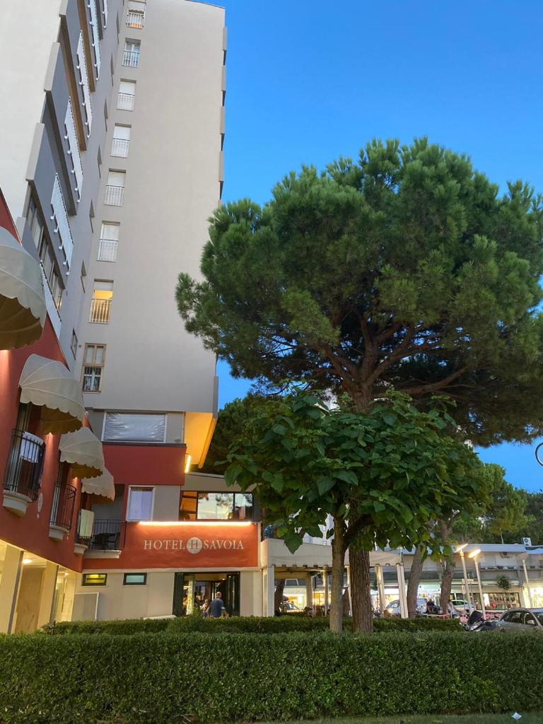 un arbre devant un grand bâtiment dans l'établissement Hotel Savoia, à Lignano Sabbiadoro