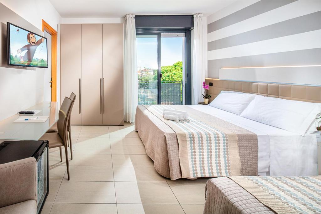 une chambre d'hôtel avec deux lits et un bureau dans l'établissement Hotel Helvetia, à Lignano Sabbiadoro