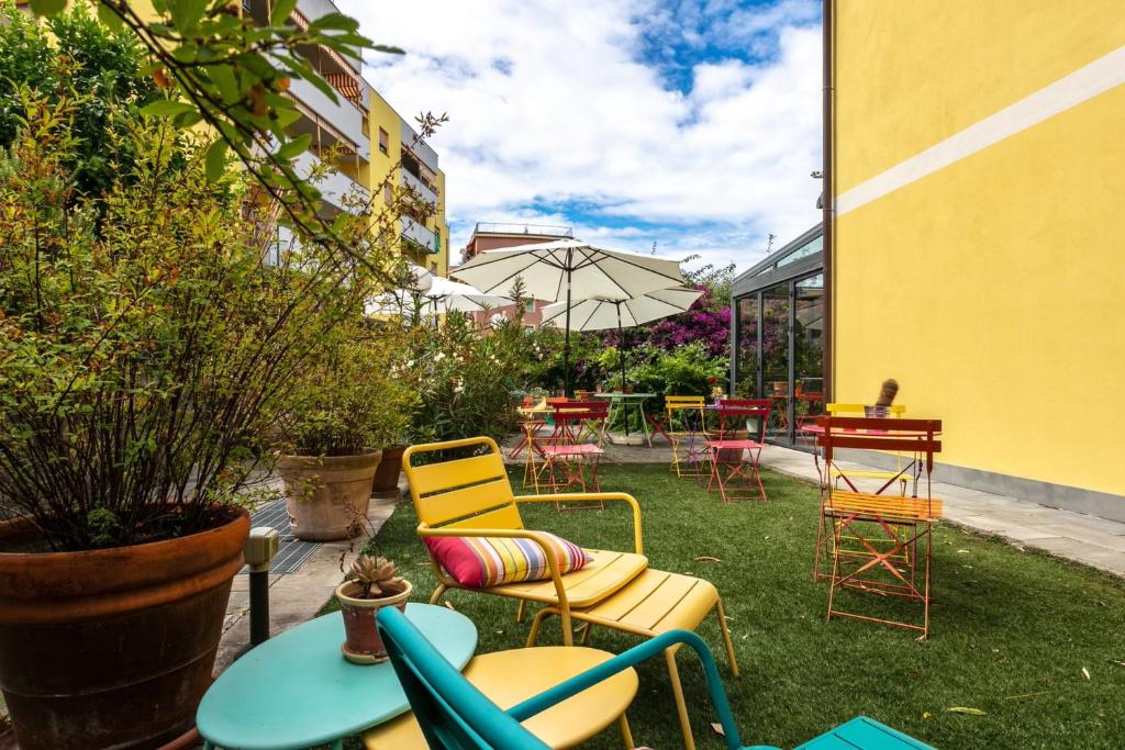 une terrasse avec des chaises, des tables et un parasol dans l'établissement Oasi Hotel, à Levanto