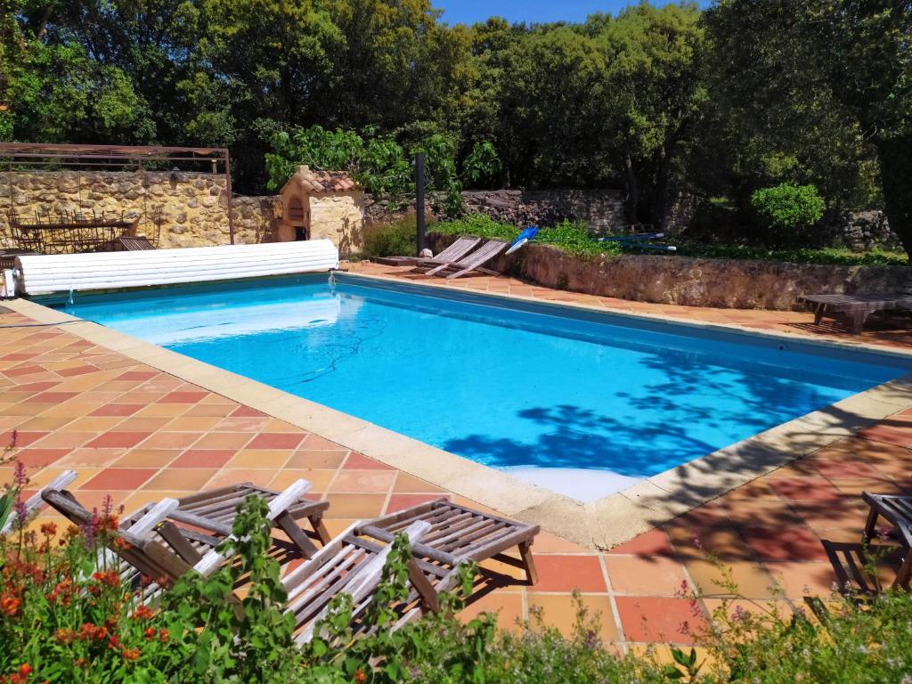 une piscine avec deux chaises et une table dans l'établissement Le Mas Draiou Ecogites - 2 gites et une chbre familliale combinables 14 pers, à Saint-Restitut