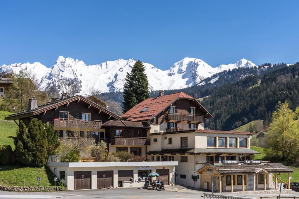 un grand bâtiment avec des montagnes enneigées en arrière-plan dans l'établissement Le Rookie Mountain, au Grand-Bornand