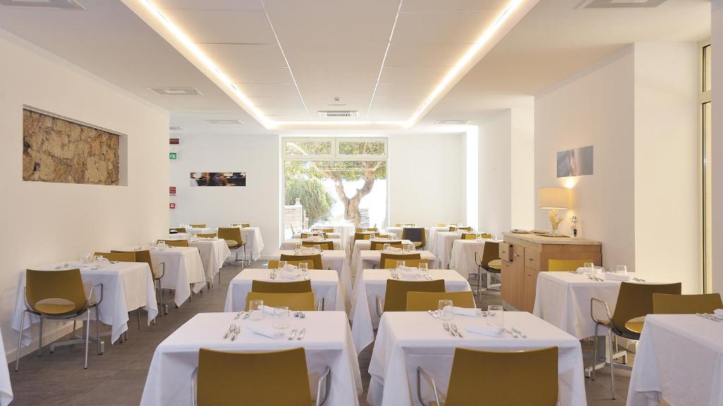 une salle à manger avec des tables et des chaises blanches dans l'établissement Hotel Club Torre Salinas - Adults Only, à Muravera