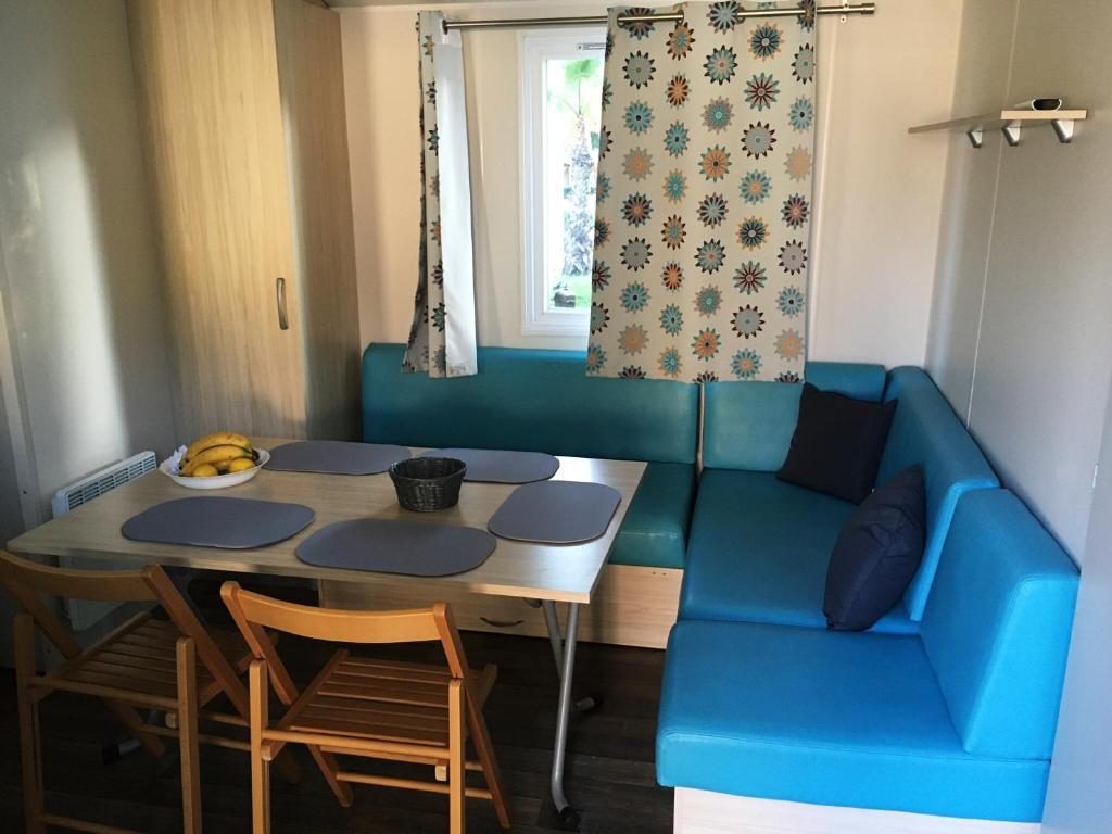 un salon avec un canapé bleu et une table dans l'établissement Mobil Home pour 6 personnes climatisé à quelques minutes des plages, à Agde