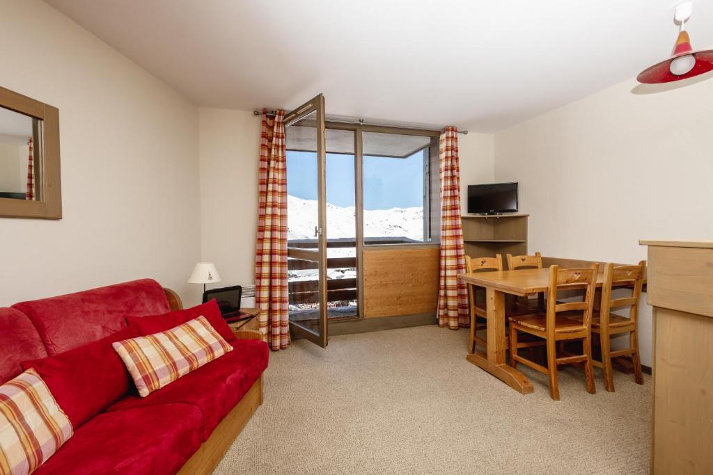 un salon avec un canapé rouge et une table dans l'établissement Résidence Le Chamois d'Or, à Val Thorens