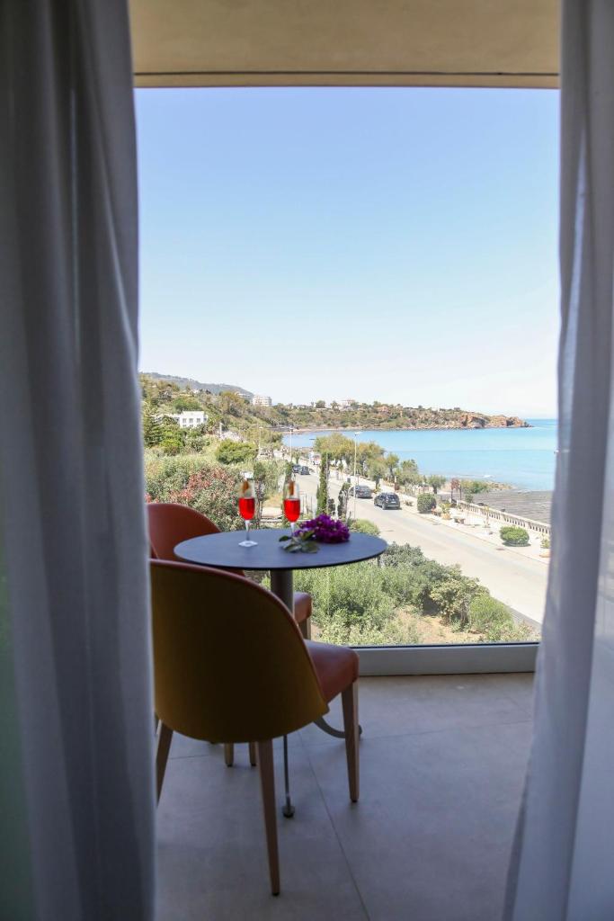 une table avec des boissons et une vue sur l'océan dans l'établissement Sunset Hotel, à Cefalù