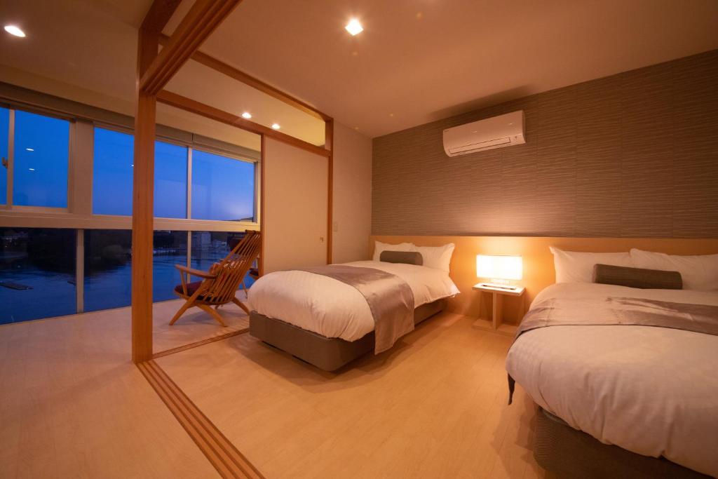 une chambre avec deux lits et une grande fenêtre dans l'établissement Toba Grand Hotel, à Toba