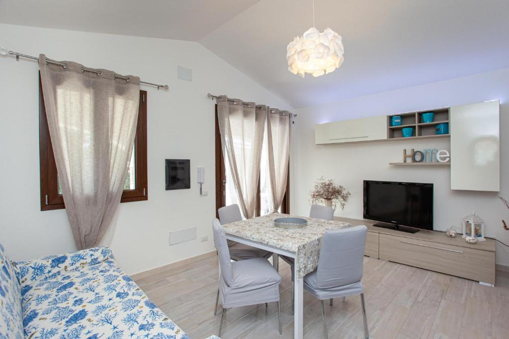 un salon avec une table, des chaises et une télévision dans l'établissement Oasi del relax, à Budoni