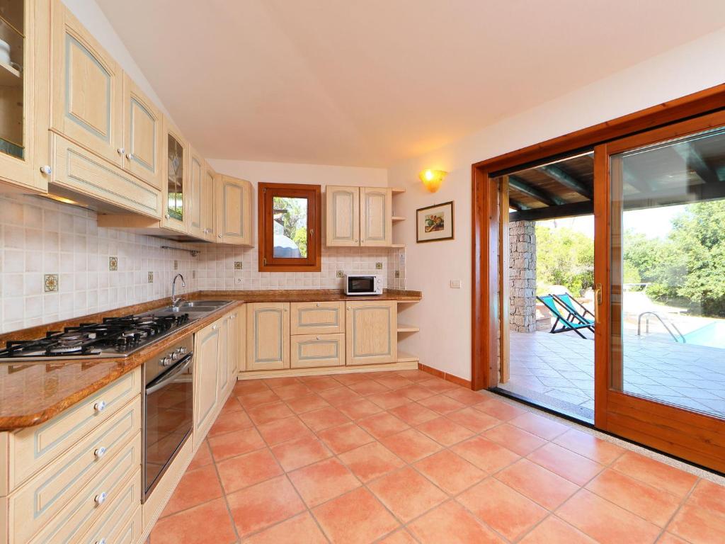 une cuisine avec des placards blancs et une porte coulissante en verre. dans l'établissement Villa Petra Rossa by Interhome, à Li Valcaggi