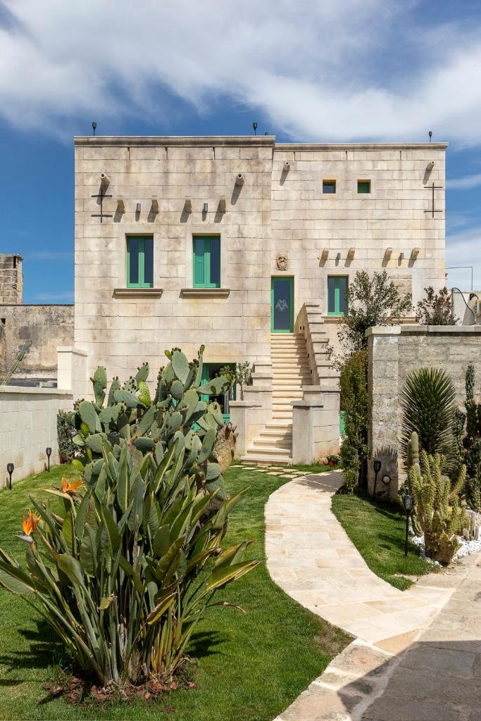 - un grand bâtiment en pierre avec des fenêtres vertes dans l'établissement Palazzo Ducale Venturi - Luxury Hotel & Wellness, à Minervino di Lecce